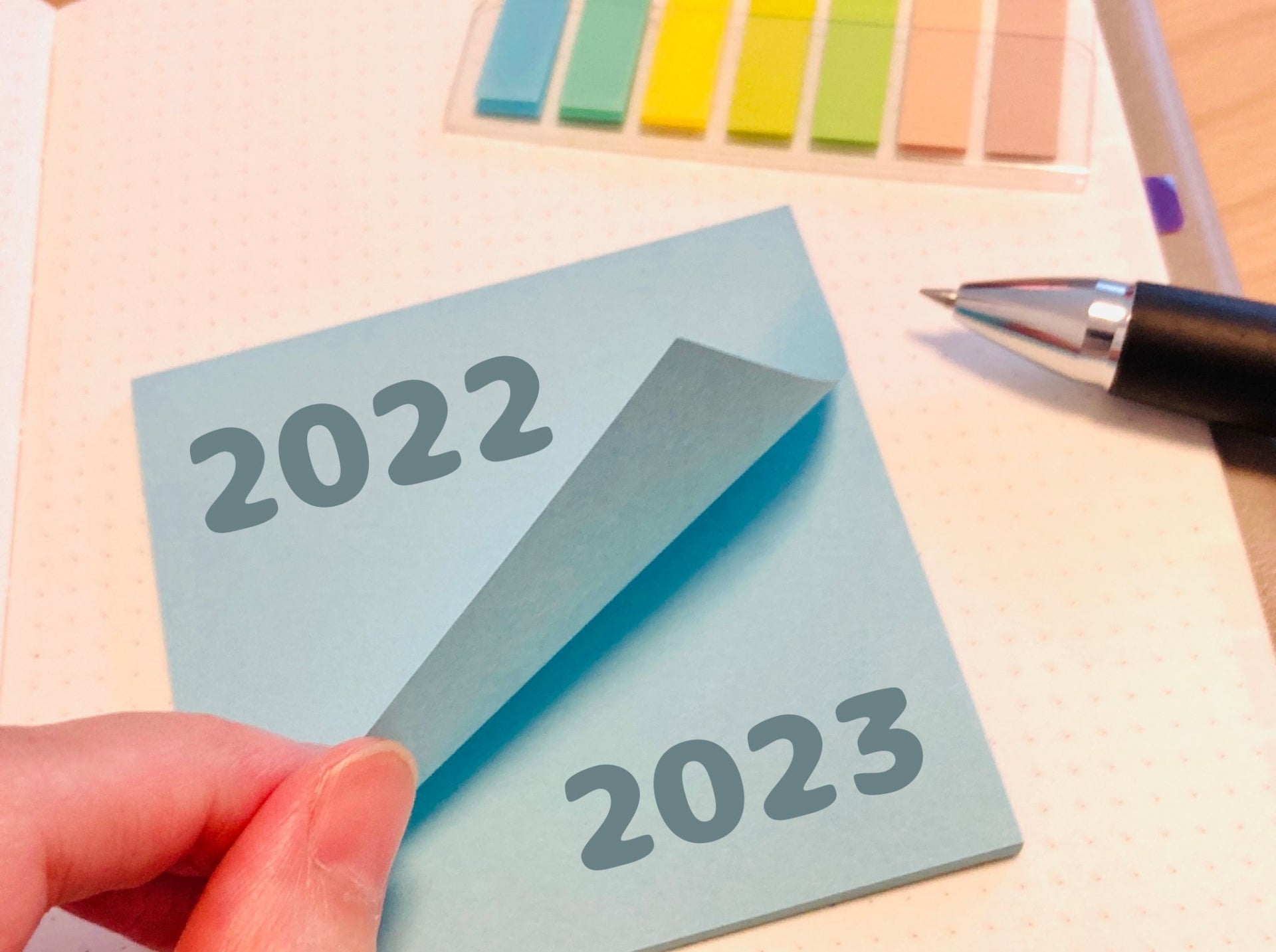 「2022」と書かれた水色の付箋を手でめくると下に「2023」の文字が現れ、年が変わる瞬間を表した場面