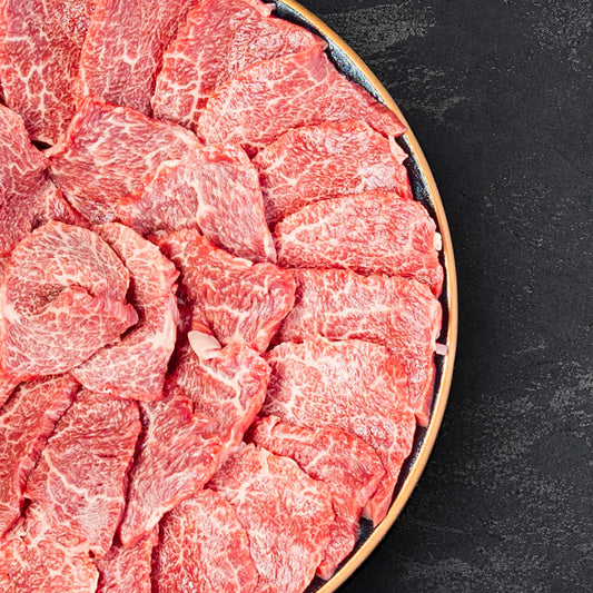 和牛セレブの近江牛焼肉ロース1kgを黒い大皿に丁寧に並べた生肉のカット。赤身と霜降りのバランスが美しく、薄切りスライスが放射状に盛り付けられている