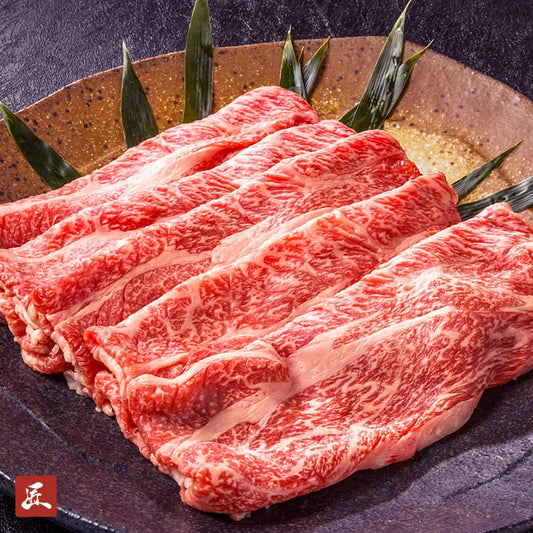 霜降りの入った近江牛モモスライスが黒い陶器の皿に扇状に並べられ、笹の葉が添えられている