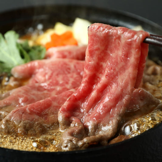 すき焼き鍋で煮えた黒毛和牛のスライスを箸でつまみ上げた瞬間で、艶やかな霜降りと甘辛いだし汁がたっぷりと絡んでいる