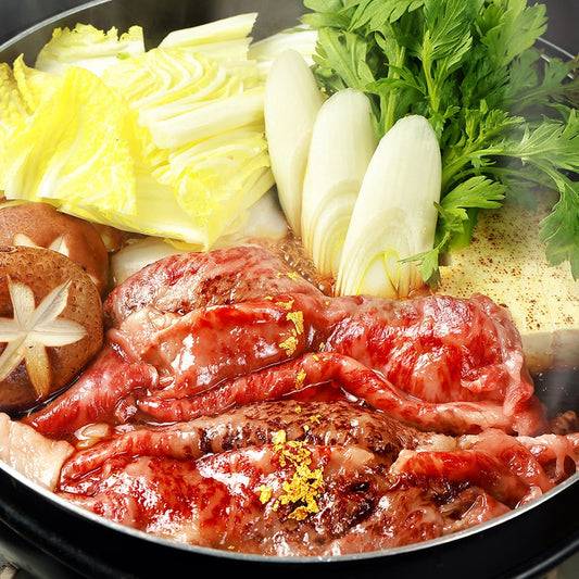 飛騨牛の赤身モモ肉がすき焼き鍋で割り下に煮られ、白菜やネギ、しいたけとともに金箔を散らした状態で盛りつけられている