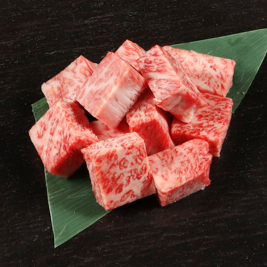 葉の上に積み上げられた松阪牛A5等級サイコロカットの霜降り牛肉、きめ細かなサシが均一に入った断面がよく分かる接写