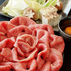 松阪牛ロースのすき焼き用薄切り肉が花形に盛られ、白菜・豆腐・しいたけ・卵などの具材とともにテーブルに並んでいる