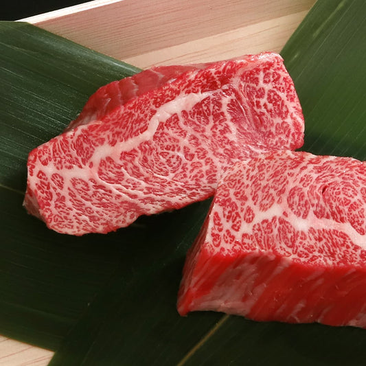 竹の葉を敷いた木製トレーに松阪牛カルビステーキ2切れが並び、きめ細かな霜降りの模様が鮮明に映し出されている