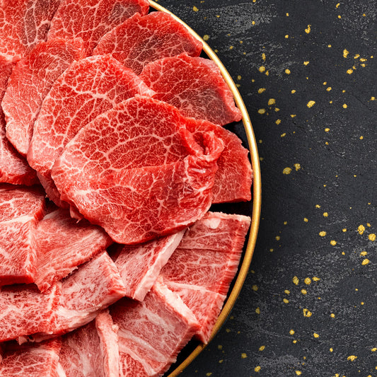 金縁の円皿に盛られた米沢牛ロースの薄切り肉、均一に広がるきめ細かな霜降りが黒いテーブルの上で鮮やかに映える