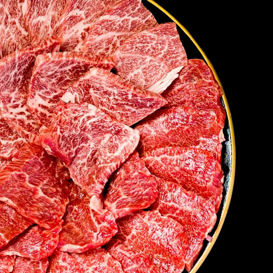佐賀牛と長崎和牛の肩ロース焼肉、きめ細かな霜降りが全面に入った薄切り生肉を金縁の丸皿に扇状に並べたクローズアップ