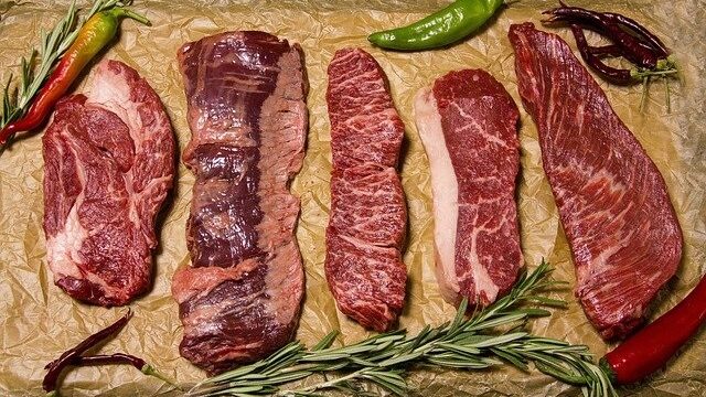 クラフト紙の上に並べられた6種類の生の和牛カット肉とローズマリー、赤と緑の唐辛子をあしらったケトジェニックダイエット向け高タンパク食材の紹介