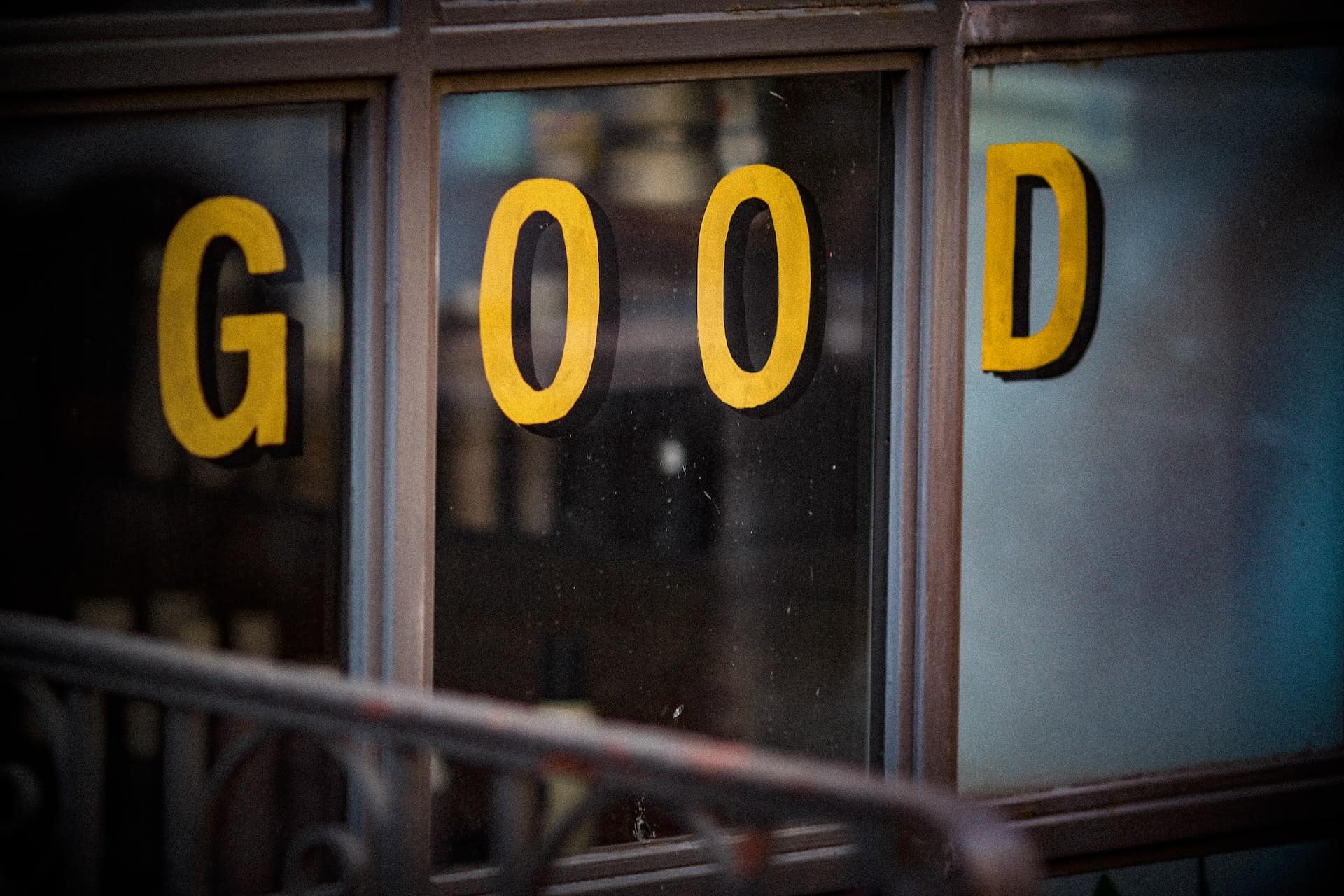 黄色い文字でGOODと書かれたショーウィンドウのガラス越しに通りが映り込んでいる店舗外観