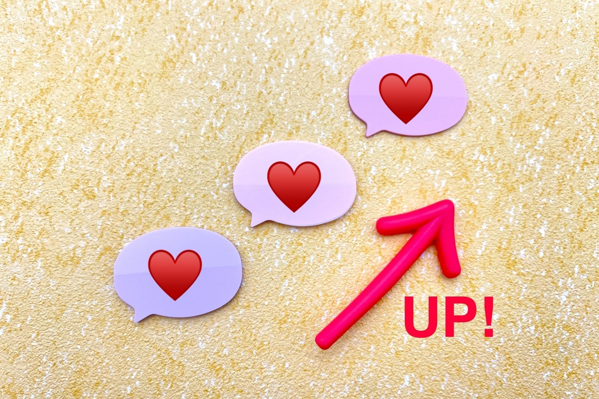 ハート入りの吹き出しが3つ並び右上がりの矢印とUPの文字が描かれた会社記念日のギフトで社員のやる気を高めるイメージのイラスト
