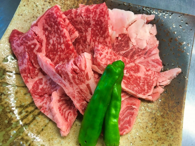 細かいサシが入った和牛のウデ肉が石皿に盛り付けられ、隣にししとうが2本添えられている焼肉用の盛り合わせ