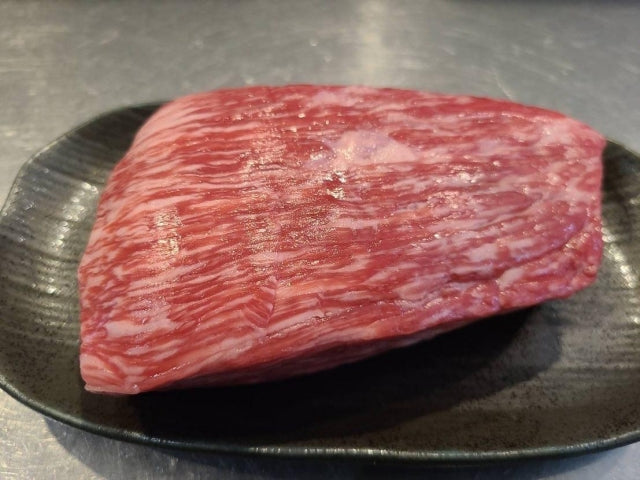 黒い皿に盛られた近江牛のブロック肉。きめ細かいサシが均一に入った赤身が特徴的で、和牛特有の美しい霜降りが確認できる