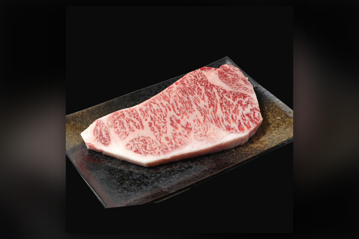 宮崎牛の特上ロースステーキ。きめ細かなサシが全面に入った実物の一枚を黒い皿に盛り付けた実物写真