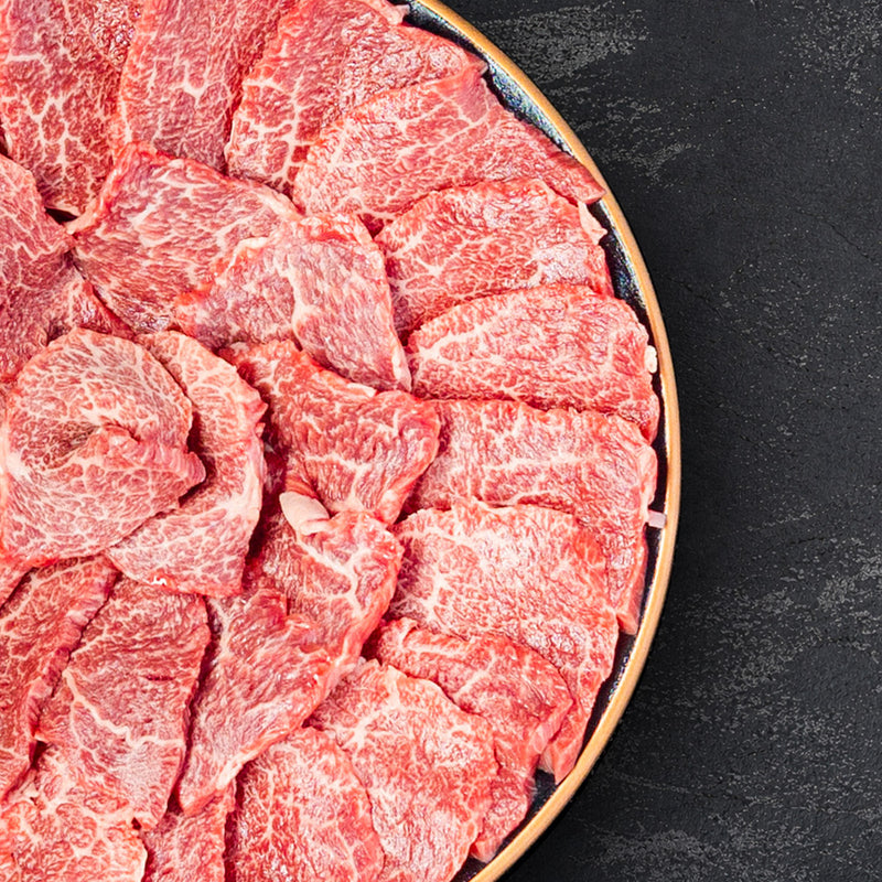 和牛セレブの近江牛焼肉ロース1kgを黒い大皿に丁寧に並べた生肉のカット。赤身と霜降りのバランスが美しく、薄切りスライスが放射状に盛り付けられている