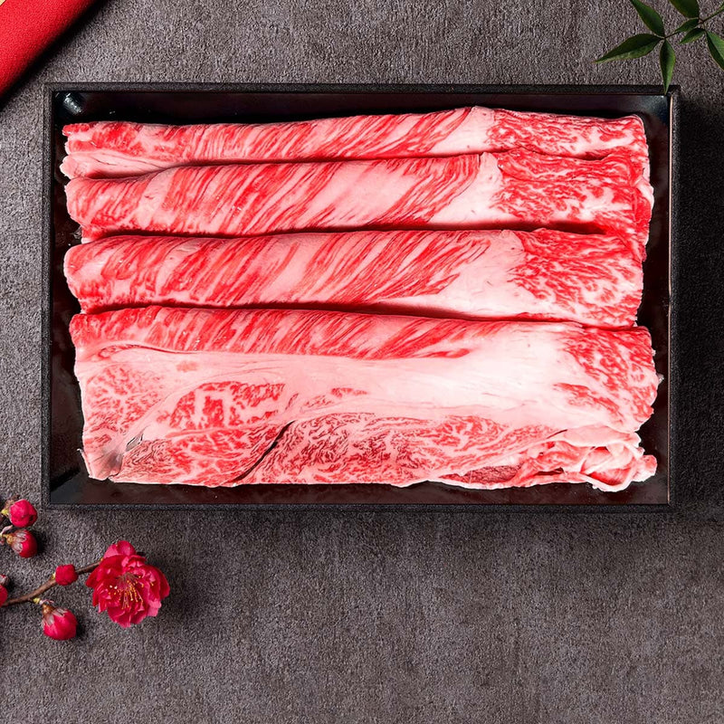 和牛セレブの神戸牛しゃぶしゃぶ用モモ・ウデ150g、艶やかな霜降りの薄切り肉が黒いトレーに整然と並び、赤い梅の花が添えられている