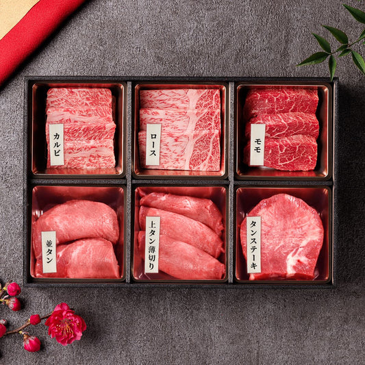 鳥取和牛焼肉3種と牛タン3種を6区画の黒い仕切り箱に盛り付けた焼肉セット。それぞれの部位に白いラベルが付き、霜降りと赤身の対比が際立つ