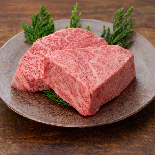 飛騨牛ランプ生ステーキ2枚を土皿に盛り側面からとらえた肉質のアップ。濃い赤身と均一に走るサシの美しいコントラストがよくわかる