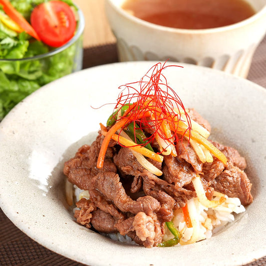 飛騨牛赤身の焼肉を使ったビビンバ丼が白い器に盛られ、細切り野菜と糸唐辛子をトッピングしてサラダとスープとともに並んでいる