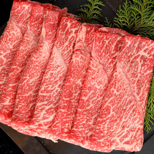 飛騨牛モモスライスを黒いプレートに広げた状態で、赤身に白い霜降りが均一に入った鮮やかな肉質が確認できる