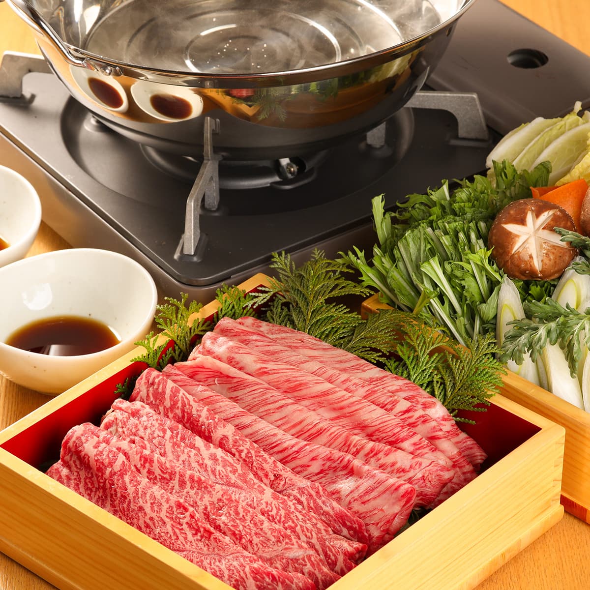 飛騨牛のしゃぶしゃぶ用スライス肉が木箱の器に重ねて盛られ鍋と野菜とポン酢が添えられたしゃぶしゃぶ膳の全景