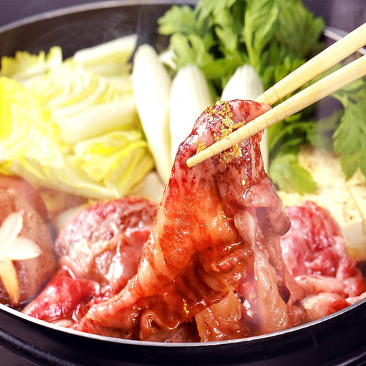 すき焼き鍋から箸でつまみ上げた黒毛和牛スライスに金箔が輝き、白菜や三つ葉とともに鍋の豪華な情景が広がる
