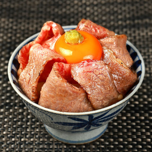 仙台牛バラカルビをレアに焼き上げた肉丼で、藍染め模様の和器に盛られた肉の上に黄身と山葵をのせた贅沢な一杯