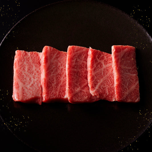 能登牛牛肩ウデ焼肉の赤身スライス5枚が黒い丸皿に扇状に並べられ、金の粒子が散らされた背景に映えている