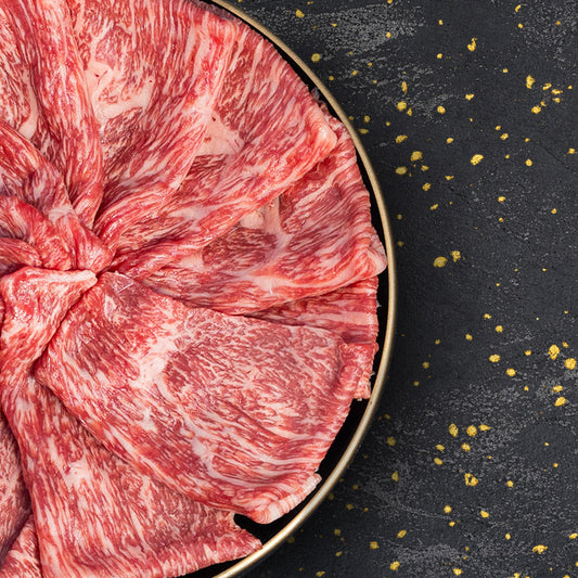 黒いプレートに扇形に並べた米沢牛モモ薄切り肉のきめ細かな霜降りと赤身のコントラスト