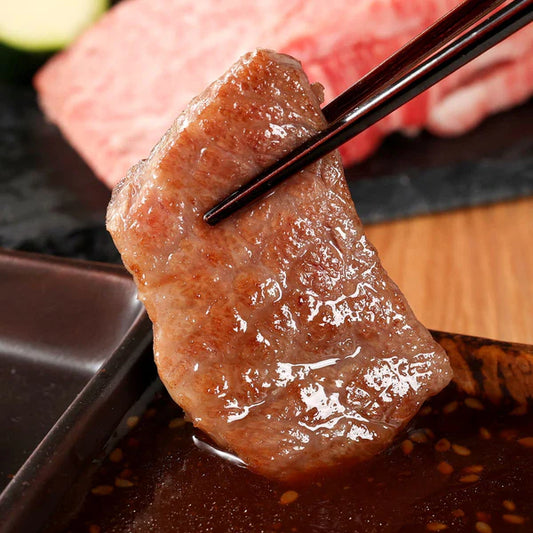 箸でつまんだ近江牛バラ肉が焼き上がり、脂が溶け出してつやつやと光り食欲をそそる焼肉シーン